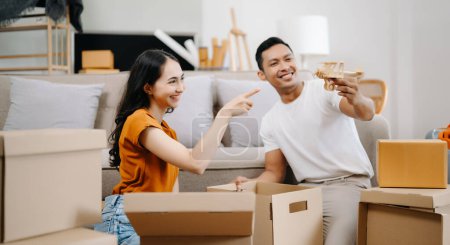 Photo for Happy asian young attractive couple man and woman with big boxes moving into a new house - Royalty Free Image