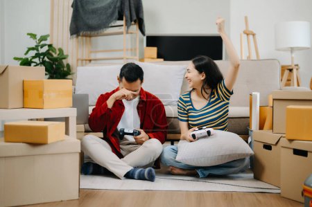 Téléchargez les photos : Asiatique jeune couple attrayant homme et femme jouer à des jeux vidéo avec des emballages en carton sur fond, déplacer dans un nouveau concept de maison - en image libre de droit
