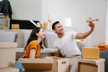 Téléchargez les photos : Jeune couple avec de grandes boîtes emménageant dans une nouvelle maison. Asiatique homme et femme aider à soulever des boîtes pour la nouvelle maison - en image libre de droit