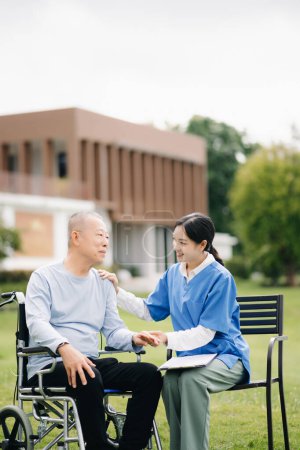 Téléchargez les photos : Personnes âgées asiatique senior homme en fauteuil roulant avec asiatique soignant soignant et encourager le patient dans le jardin. - en image libre de droit