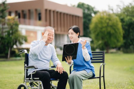 Téléchargez les photos : Aîné asiatique homme âgé en fauteuil roulant avec soignant asiatique soignant. Soins infirmiers dans le jardin de l'hôpital - en image libre de droit