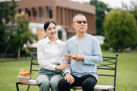 Téléchargez les photos : Heureuse petite-fille adulte et grand-père aîné assis en plein air dans le parc - en image libre de droit