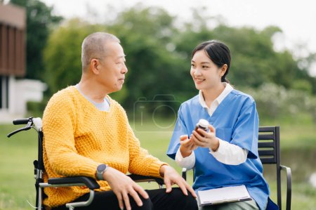Téléchargez les photos : Aîné asiatique homme âgé en fauteuil roulant avec soignant asiatique soignant. Soins infirmiers dans le jardin de l'hôpital - en image libre de droit