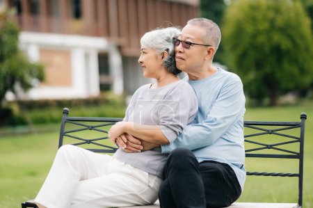 Téléchargez les photos : Asiatique couple âgé passer un bon moment. Ils rient et sourient assis à l'extérieur sur le banc du parc. Charmant couple senior - en image libre de droit