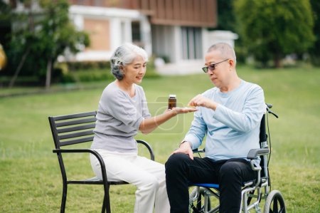 Photo for Asian Senior man sitting in wheelchair, woman taking care of each other, romantic time. They laughing and smiling outdoor in the park - Royalty Free Image