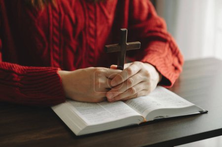 Photo for Woman sitting and studying the scriptures.The  wooden cross in the hands. Christian education concepts The Holy Scriptures open and pray to God - Royalty Free Image