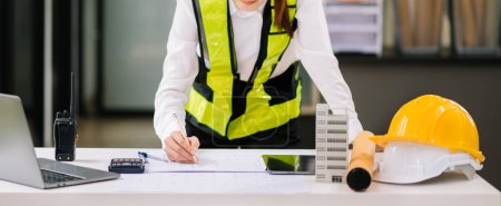 Photo for Business woman working on on architectural project at construction site at desk in office - Royalty Free Image