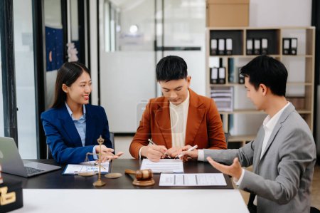 Foto de Asian Business people compasivamente tomados de la mano y discutiendo papeles contractuales en la sala de oficina - Imagen libre de derechos