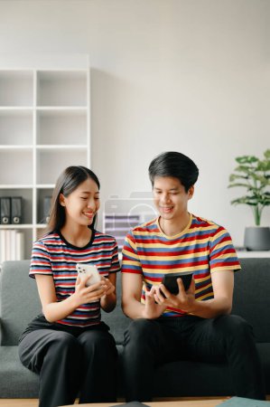 Téléchargez les photos : Deux étudiants asiatiques apprenant ensemble en ligne ensemble dans le salon à la maison - en image libre de droit
