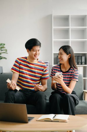 Foto de Dos estudiantes asiáticos aprendiendo juntos en línea juntos en la sala de estar en casa - Imagen libre de derechos
