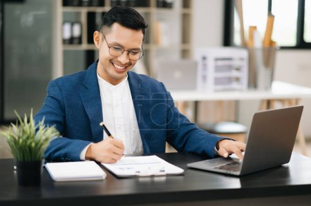 Photo for Young business man working at office with laptop in modern office - Royalty Free Image
