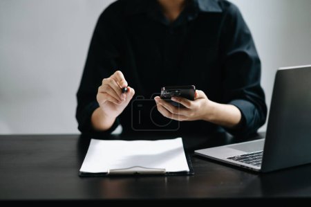 Téléchargez les photos : Femme d'affaires travaillant sur smartphone dans le bureau à la table à la lumière du matin - en image libre de droit
