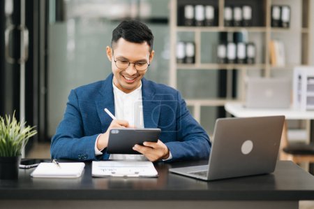 Foto de Joven hombre de negocios que trabaja en la oficina con tableta digital y portátil en la oficina moderna - Imagen libre de derechos