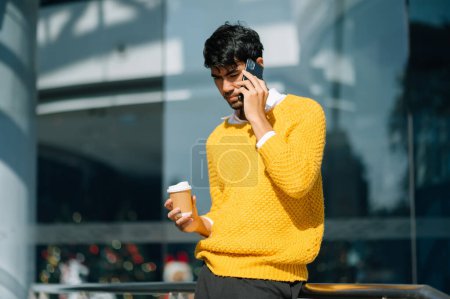 Téléchargez les photos : Homme d'affaires professionnel utilisant un smartphone et tenant du café pour aller tout en travaillant au bureau de la ville - en image libre de droit
