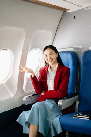 Foto de Atractiva pasajera asiática de avión sentada en asiento cómodo. Viajar con estilo - Imagen libre de derechos