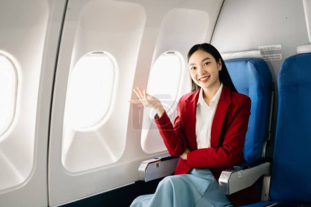 Foto de Retrato de una exitosa mujer de negocios asiática en un traje formal en un avión sentado en clase ejecutiva.Viajar con estilo, trabajar con gracia - Imagen libre de derechos