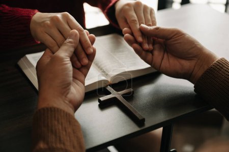 Foto de Dos personas leyendo y estudiando la Biblia en casa y orando juntas. Estudiar la Palabra de Dios con amigos - Imagen libre de derechos