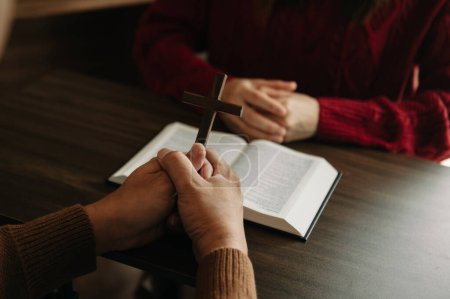 Téléchargez les photos : Deux personnes lisent et étudient la Bible à la maison et prient ensemble. Étudier la Parole de Dieu avec des amis - en image libre de droit