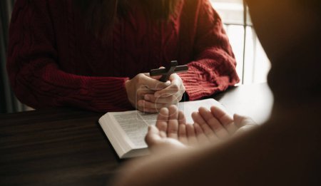 Photo for Two people reading and study bible in home and pray together. Studying the Word Of God With Friends - Royalty Free Image