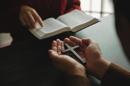 Téléchargez les photos : Deux personnes lisent et étudient la Bible à la maison et prient ensemble. Étudier la Parole de Dieu avec des amis - en image libre de droit