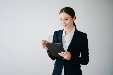 Foto de Sonriente joven mujer de negocios caucásica usando tableta digital aislada en fondo blanco - Imagen libre de derechos