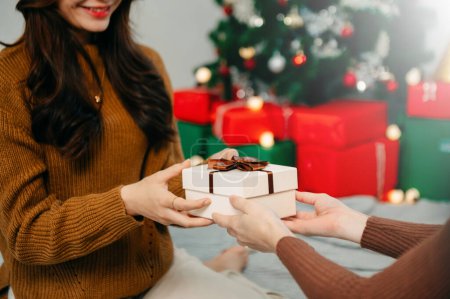 Téléchargez les photos : Bonne femme donnant Noël et Nouvel An boîte cadeau à la femme à la maison.Fête de Noël en famille. Décoration de Noël - en image libre de droit
