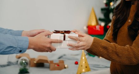 Téléchargez les photos : Cadeau de Noël entre les mains. Happy Man donnant Noël et Nouvel An boîte cadeau à la femme à la maison. Fête de Noël en famille. Décorations de Noël - en image libre de droit