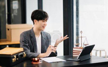 Téléchargez les photos : Asiatique avocat masculin bavarder en ligne avec le client. Discuter des détails de procès dans le bureau moderne - en image libre de droit