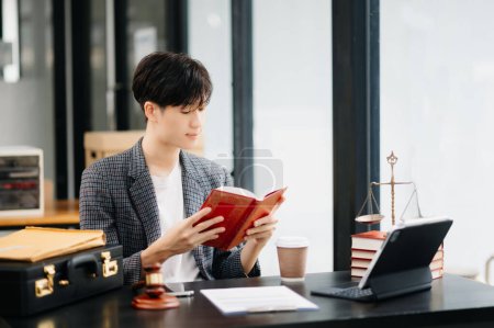 Photo for Asian Man lawyer reading legal book with gavel on table in office. justice and law ,attorney concept - Royalty Free Image