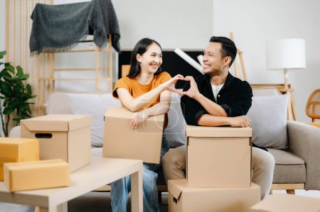 Foto de Feliz asiático joven atractivo pareja hombre y mujer con Grande cajas moviéndose en un nuevo casa - Imagen libre de derechos