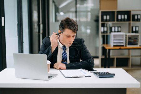 Téléchargez les photos : Jeune homme d'affaires travaillant sur ordinateur portable dans un bureau moderne - en image libre de droit