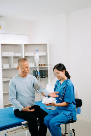Foto de Médico asiático hablando con paciente mayor y recibiendo solución salina en hospital o clínica. - Imagen libre de derechos