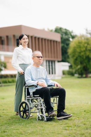 Ancianos asiático senior hombre en silla de ruedas con asiático cuidadoso cuidador en hospital jardín 