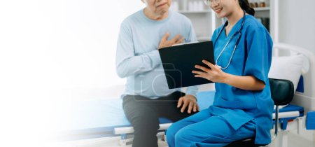 Téléchargez les photos : Médecin asiatique parlant avec un patient âgé et recevant une solution saline à l'hôpital ou à la clinique. - en image libre de droit