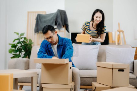 Foto de Feliz asiático joven atractivo pareja hombre y mujer con Grande cajas moviéndose en un nuevo casa - Imagen libre de derechos