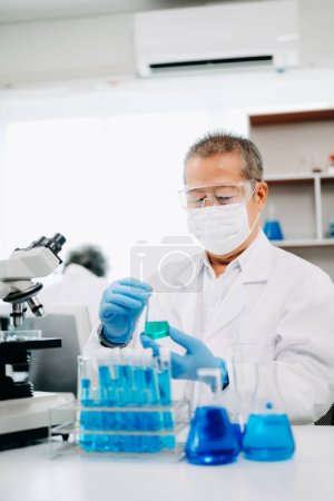 Photo for Senior scientists conducting research investigations in a medical laboratory, a researcher in the foreground is using a microscope in laboratory for medicine. - Royalty Free Image