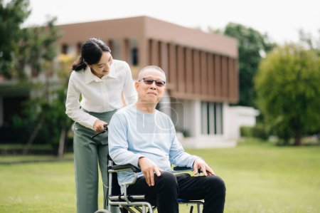 Elderly asian senior man on wheelchair with Asian careful caregiver in hospital garden 