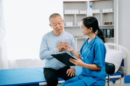 Asiatische Arzt im weißen Anzug machen Notizen während der Diskussion und asiatische ältere Menschen, Mann Patient, der auf dem Bett mit Kochsalzlösung im Krankenhaus oder in der Klinik liegt.