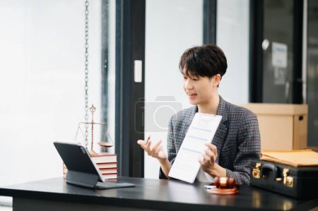 Foto de Asiático masculino abogado charlando en línea con el cliente en la tableta digital discutir detalles de la demanda. en la oficina moderna - Imagen libre de derechos