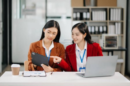 Foto de Dos empresarias asiáticas discuten proyecto de inversión de trabajo y la estrategia de planificación con ordenador portátil en la oficina - Imagen libre de derechos