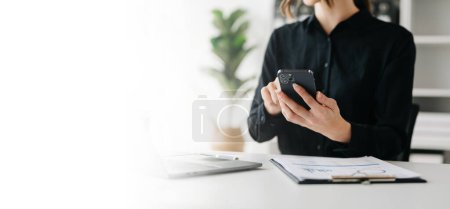Téléchargez les photos : Main de femme d'affaires en utilisant un smartphone avec un diagramme de réseau social dans le bureau - en image libre de droit