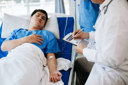 Foto de Dos doctores hablando con un paciente acostado en su cama con solución salina en el hospital - Imagen libre de derechos