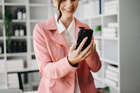 Téléchargez les photos : Main de femme d'affaires en utilisant un smartphone avec un diagramme de réseau social dans le bureau - en image libre de droit