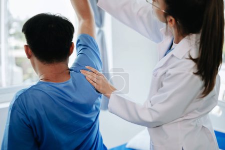 Téléchargez les photos : Médecin et patiente souffrant de maux de dos lors d'un examen médical en clinique - en image libre de droit