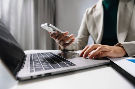 Téléchargez les photos : Mains de femme d'affaires travaillant avec ordinateur portable et smartphone avec effet de couche de stratégie d'entreprise financière sur le bureau au bureau - en image libre de droit