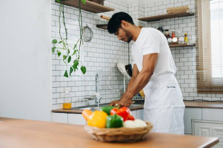 Téléchargez les photos : Image de l'homme asiatique préparant la salade dans la cuisine et des aliments sains dans un bol à la maison le matin - en image libre de droit