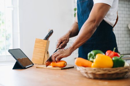 Photo for Close up young man hands preparing a healthy salad. Cutting vegetables on a cutting board on the home kitchen counter. - Royalty Free Image