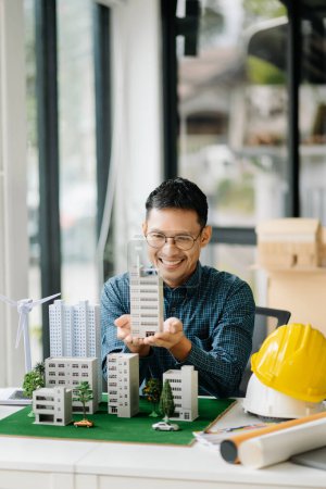 Foto de Hombre de negocios que trabaja con energía eólica en la oficina de la compañía en el sitio del proyecto arquitectónico y haciendo casa modelo - Imagen libre de derechos