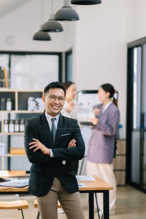 Foto de Joven atractivo asiático hombre oficina trabajador negocios trajes sonriendo a cámara en oficina - Imagen libre de derechos