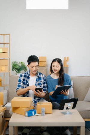 Photo for Startup small business SME, Entrepreneur owner man and woman using tablet taking receive and checking online purchase shopping order to preparing pack product box on sofa at home - Royalty Free Image